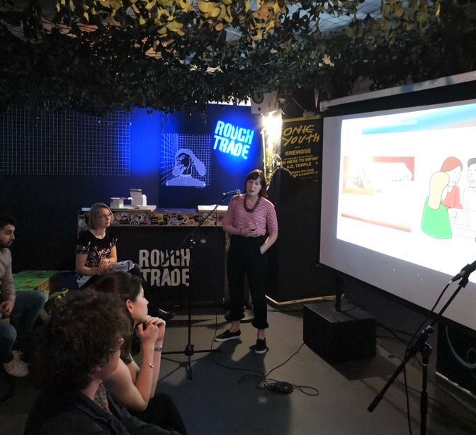 Researcher Renelle talking to people in front of a project screen